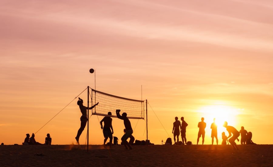 Silhouettes of volleyball players on beach